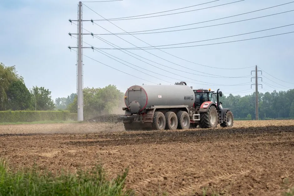Un tracteur fertilisant un champ rural avec du fumier liquide pour l'agriculture.