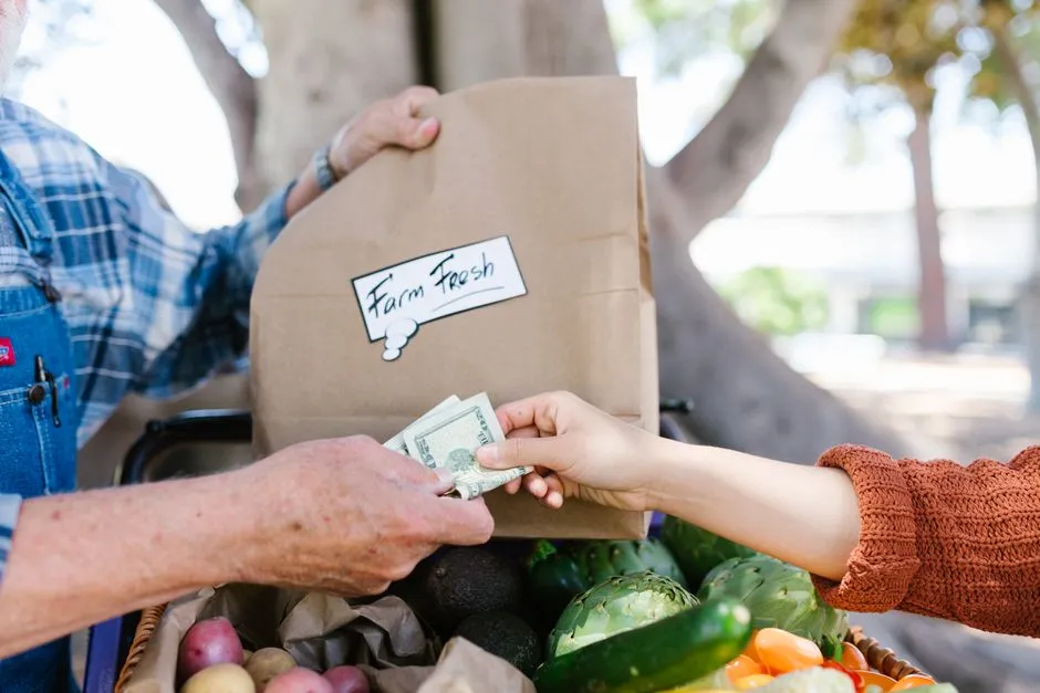 Gros plan d'une transaction au marché fermier avec des produits frais.