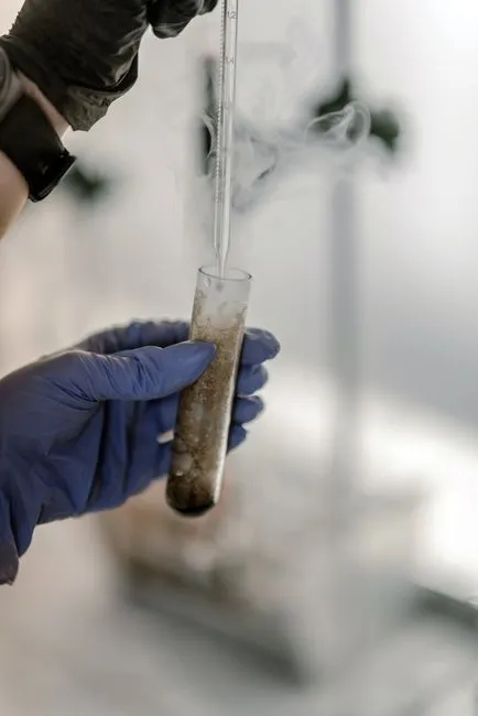 Gros plan sur les mains d'un scientifique réalisant une expérience avec de la fumée dans un environnement de laboratoire.
