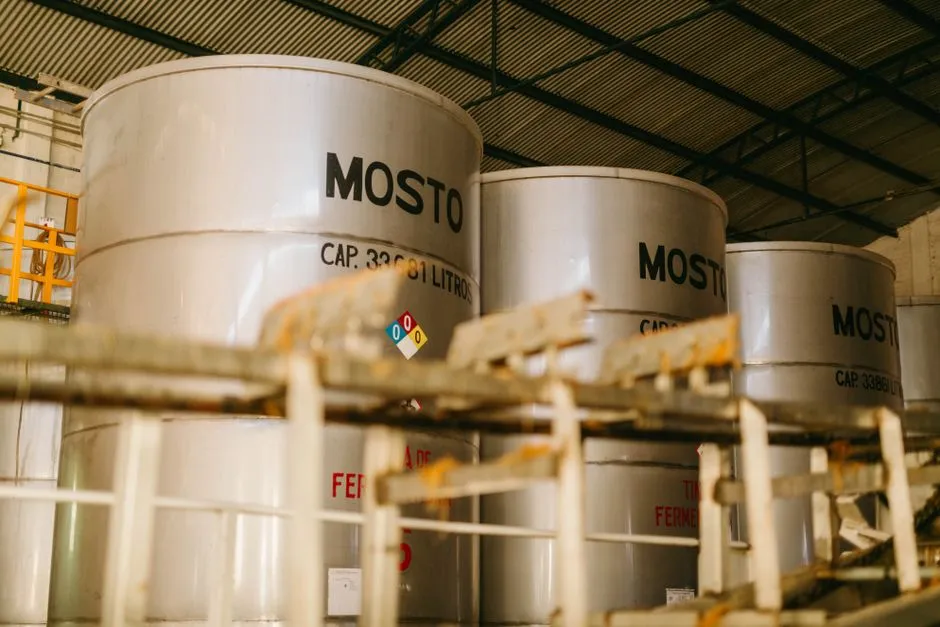 Vue intérieure d'une distillerie industrielle de tequila avec de grands conteneurs en métal étiquetés 'Mosto'.