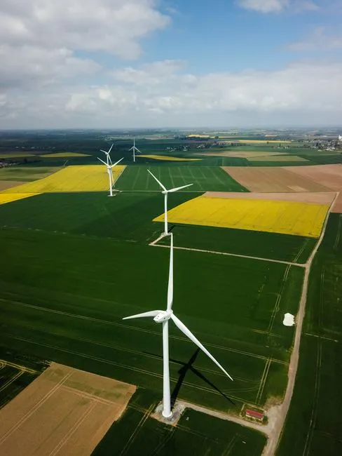 Photo par drone d'éoliennes dans des champs agricoles vibrants en France.
